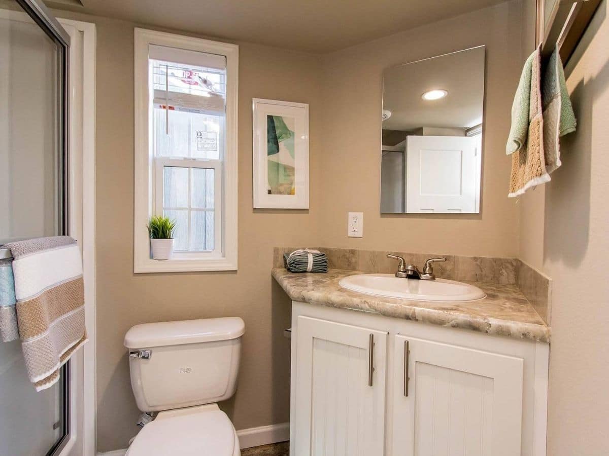 white flush toilet against cream wall next to corner vanity