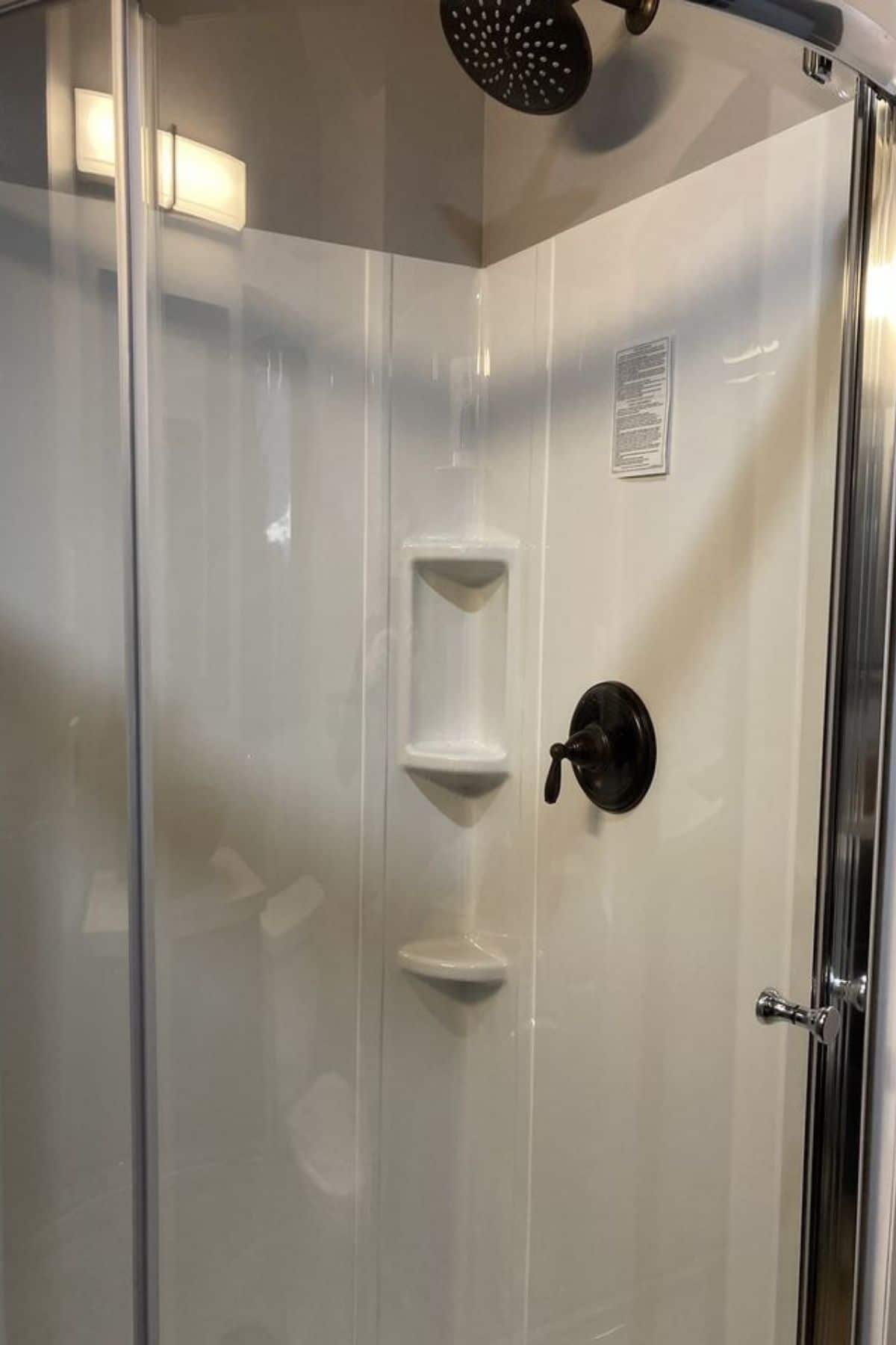 glass shower stall with white surround and built in shelves