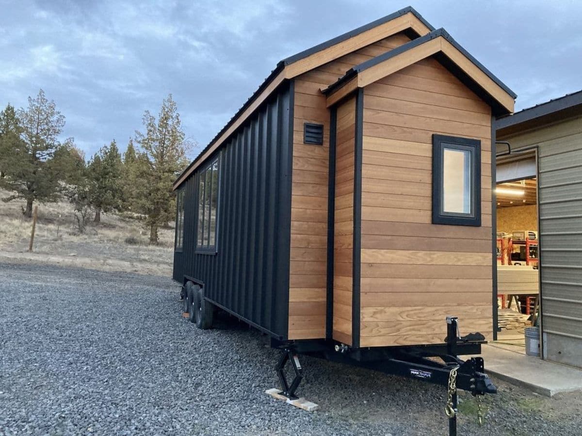 wood and black tiny house on lot with window on end of house