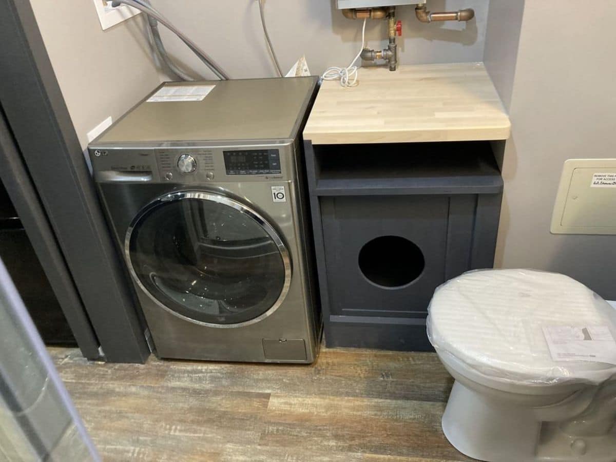 combination washer and dryer next to blue vanity and white flush toilet