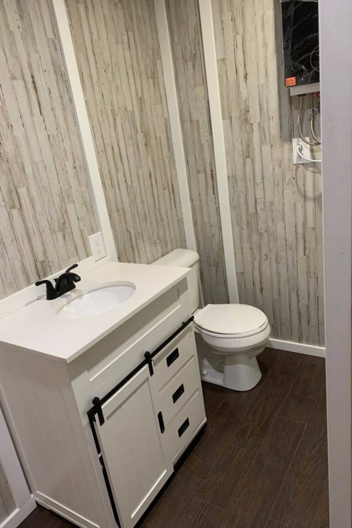 gray and white paneling on bathroom walls by white vanity and toilet