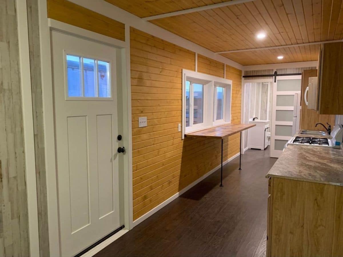 white door against wood paneling inside semi truck tiny home