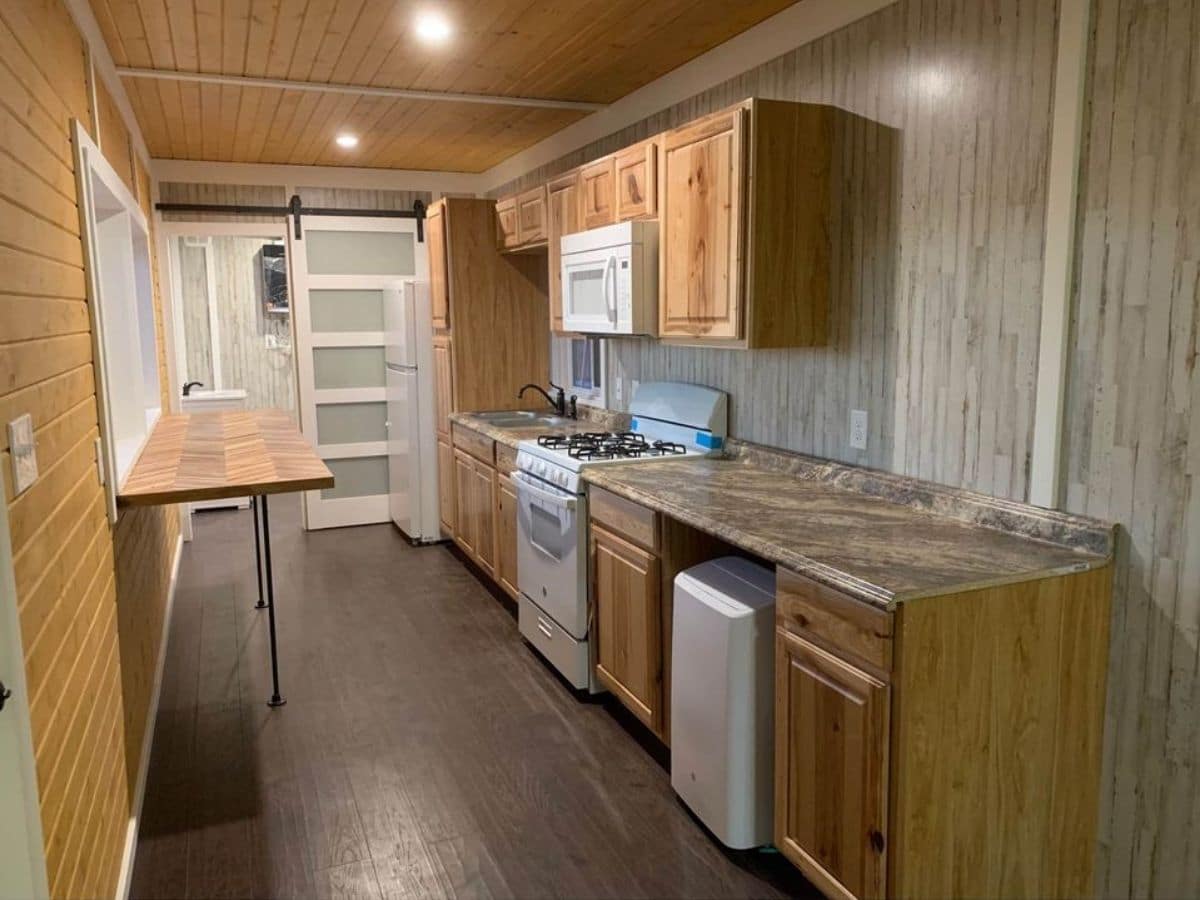 wood cabinets and counters with white appliances on right wall in tiny home