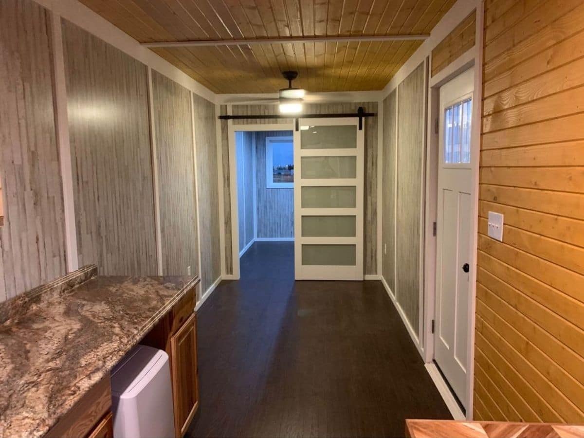view down tiny home living area with gray and white door at end