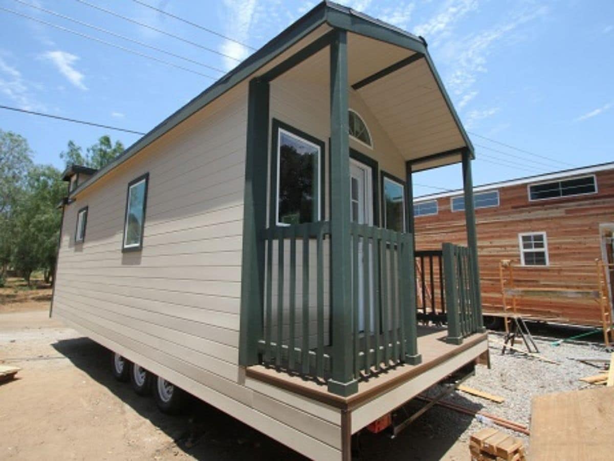 side of cream tiny house with green trim