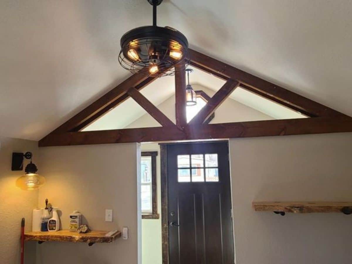 round fan and light on ceiling by front door with wood rafters