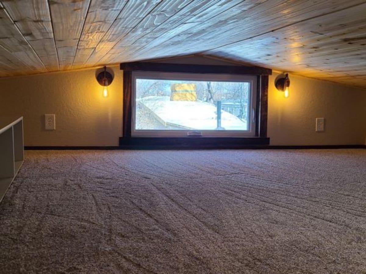 carpeted loft with window at back wall