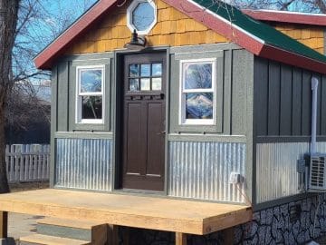 Front door of tiny home with metal siding and small porch
