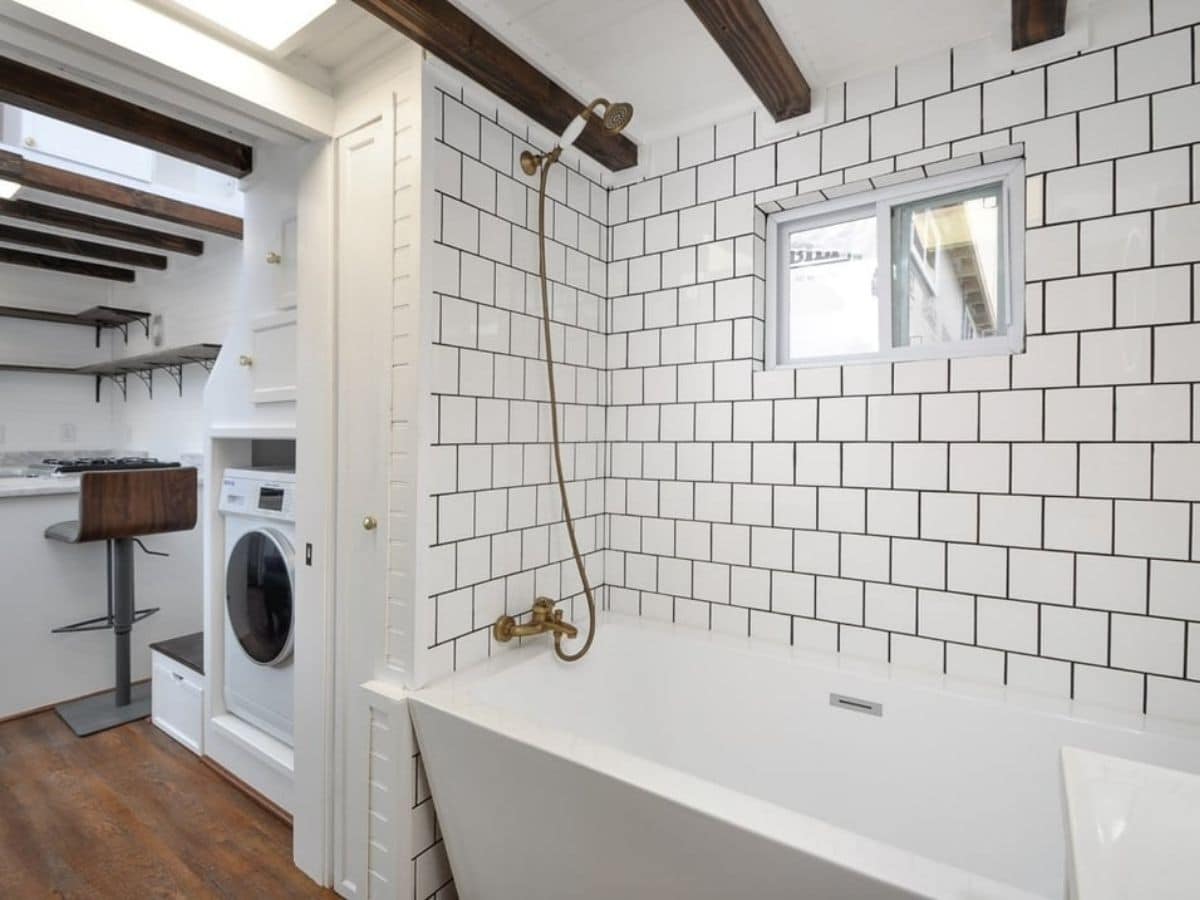 bathroom with tile behind white bathtub