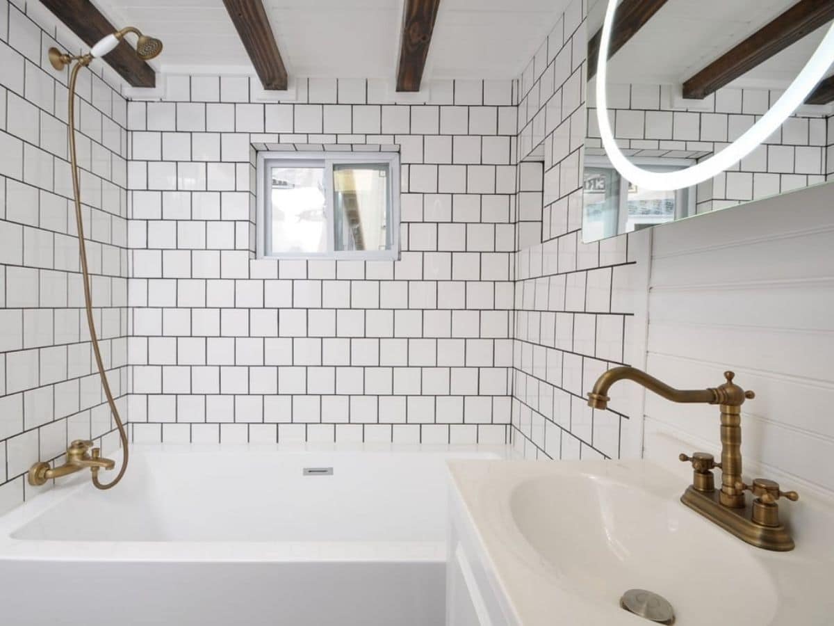 bathtub and shower with tile background and gold fixtures