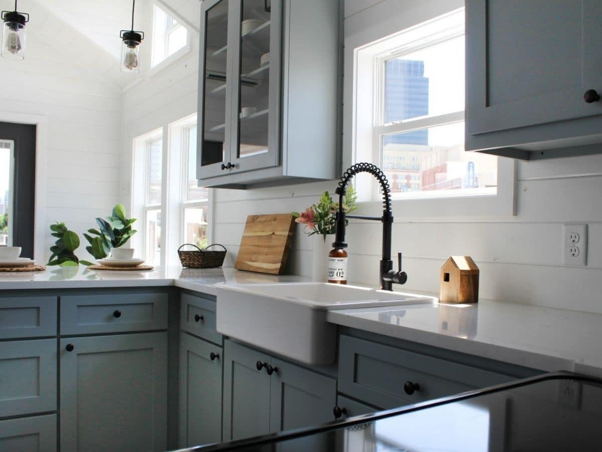 white farmhouse sink in white counters above blue cabinets