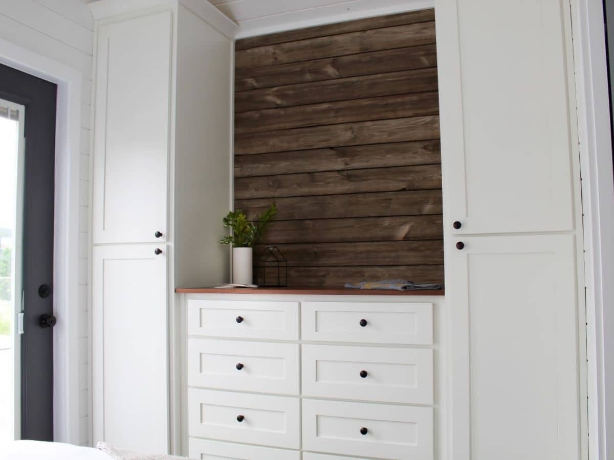 white wardrobes on both sides of chest of drawers with wood background