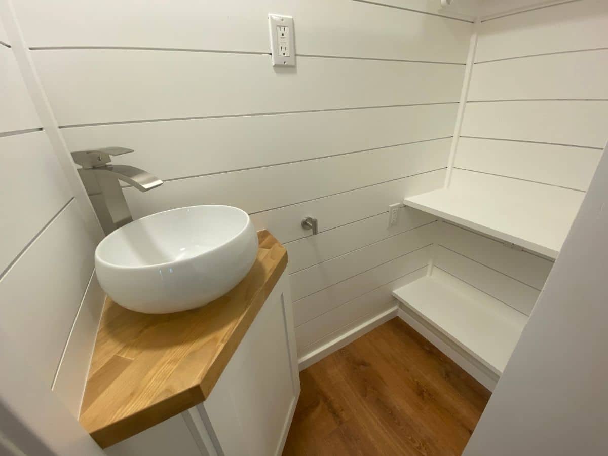bathroom with white bowl sink on top of butcherblock counter of corner cabinet