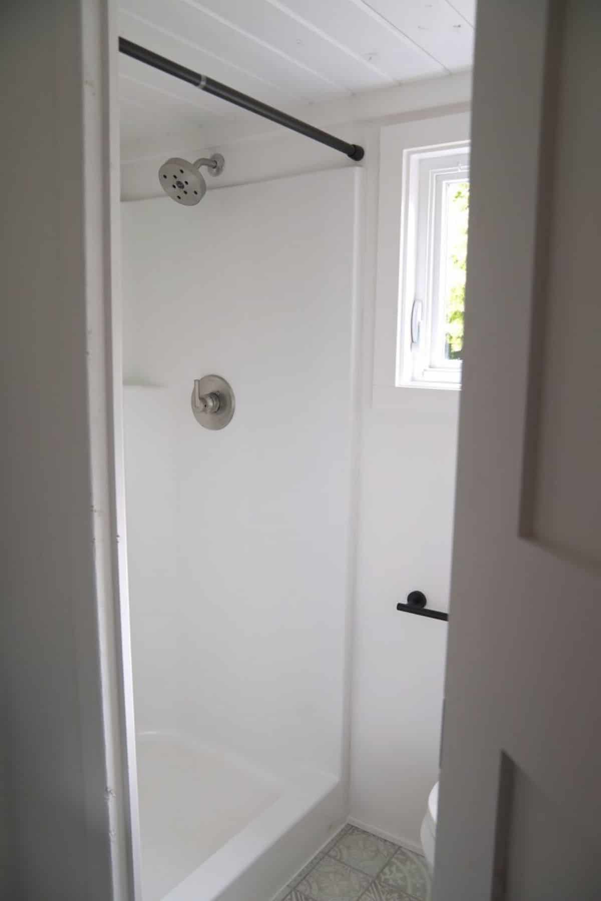 white shower stall with black rod