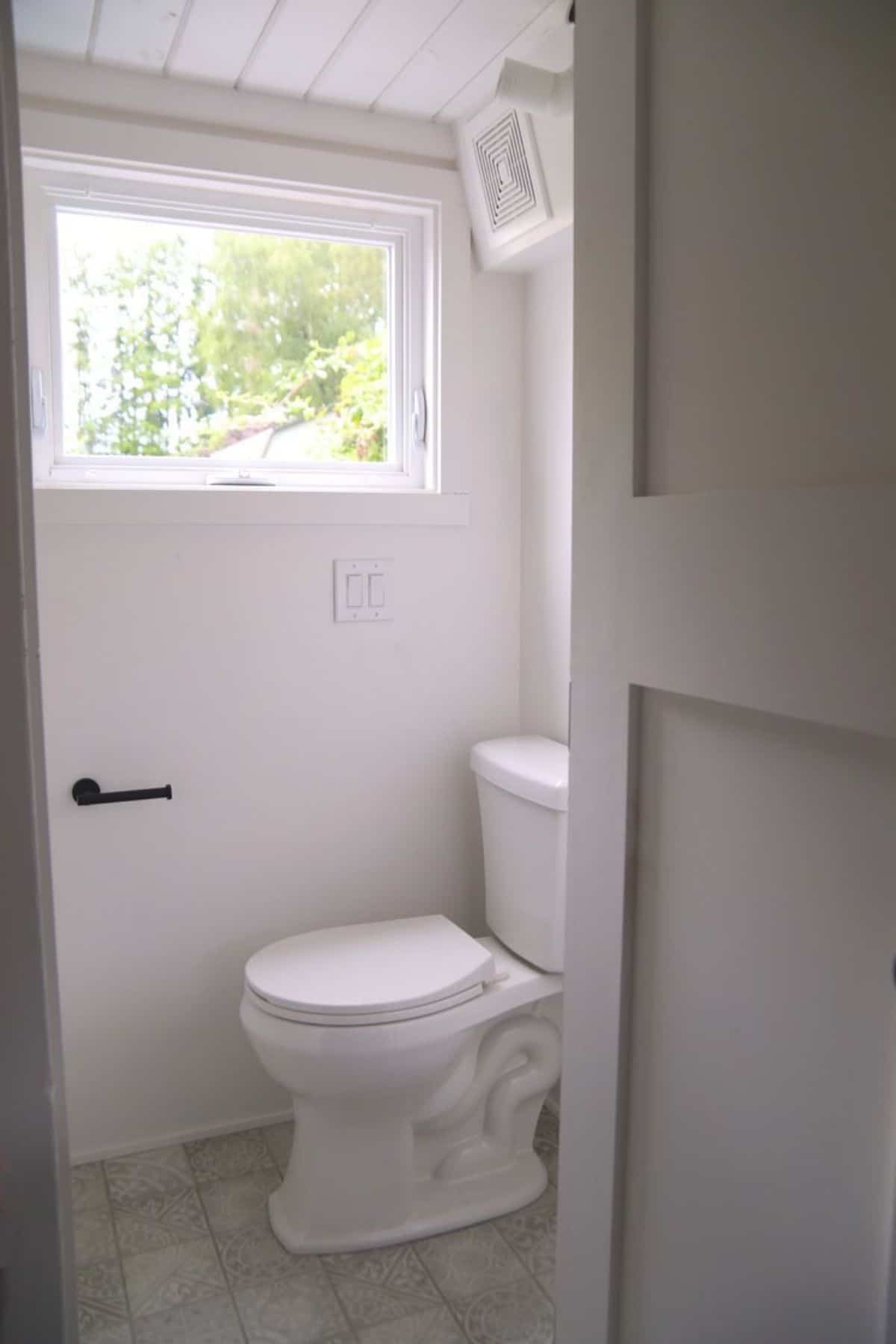 white flush toilet behind white bathroom door