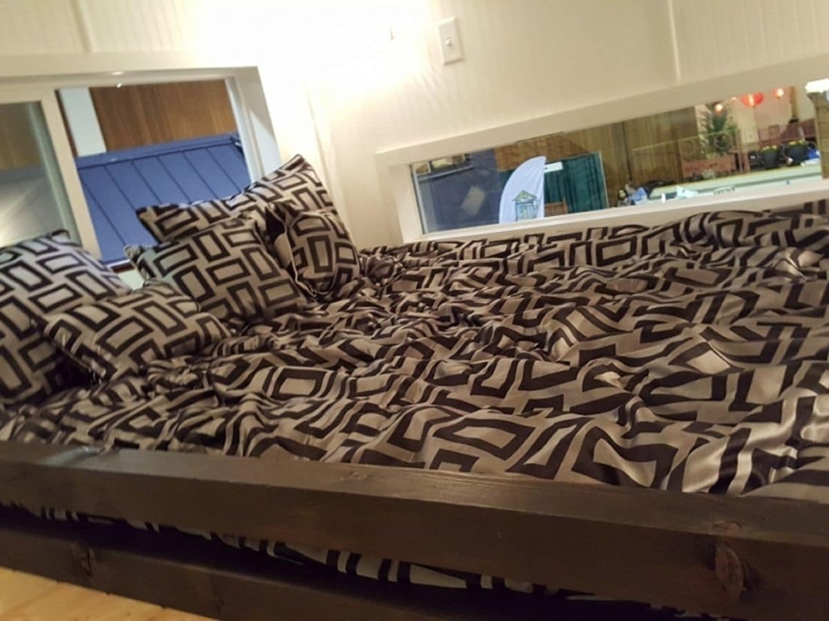 patterned black and white blanket on top of bed inl oft
