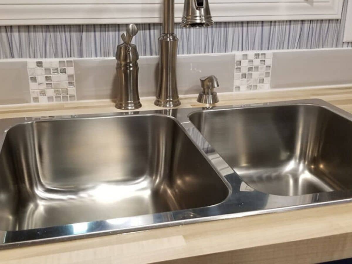 stainless steel sink in butcher block counter with tile backsplash