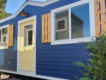 blue tiny home with yellow front door and white trim