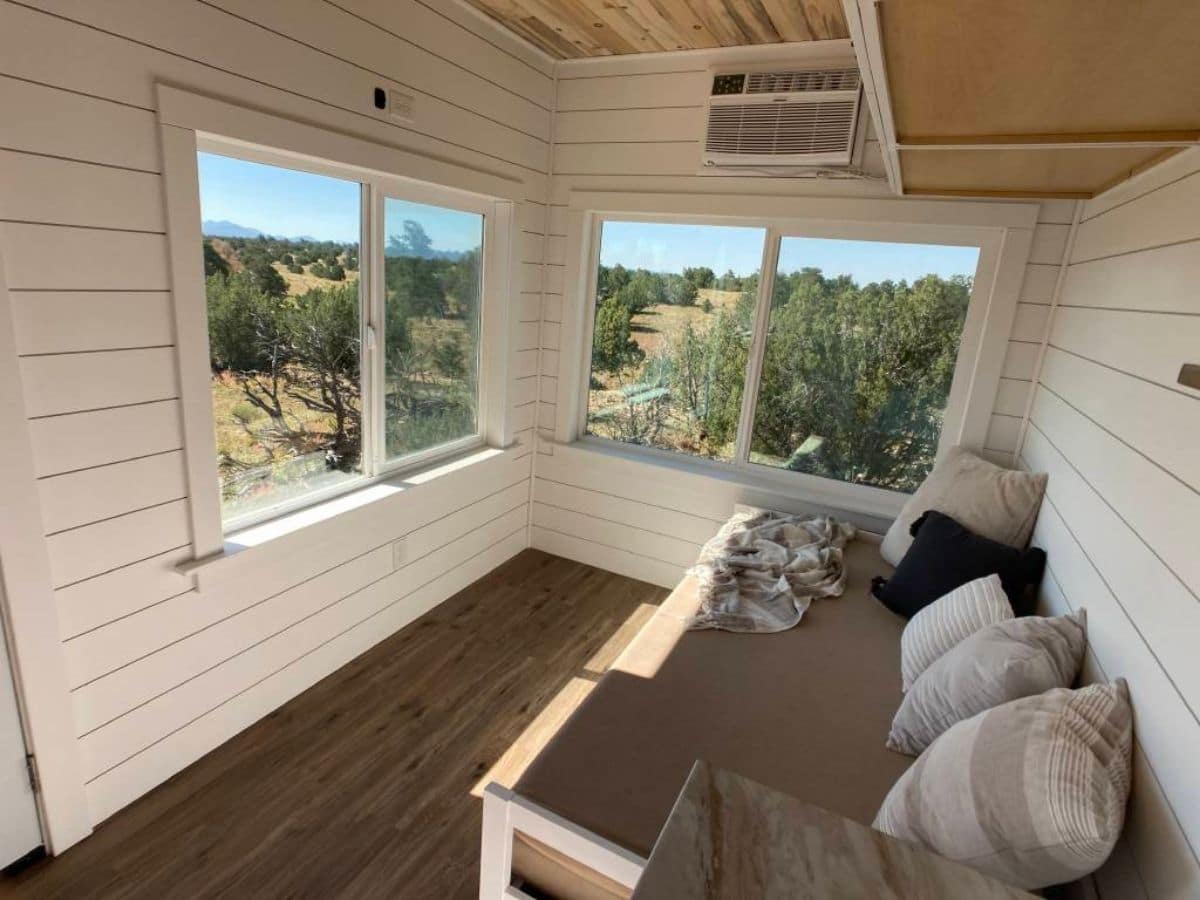 futon bed in corner of tiny home with windows on both sides