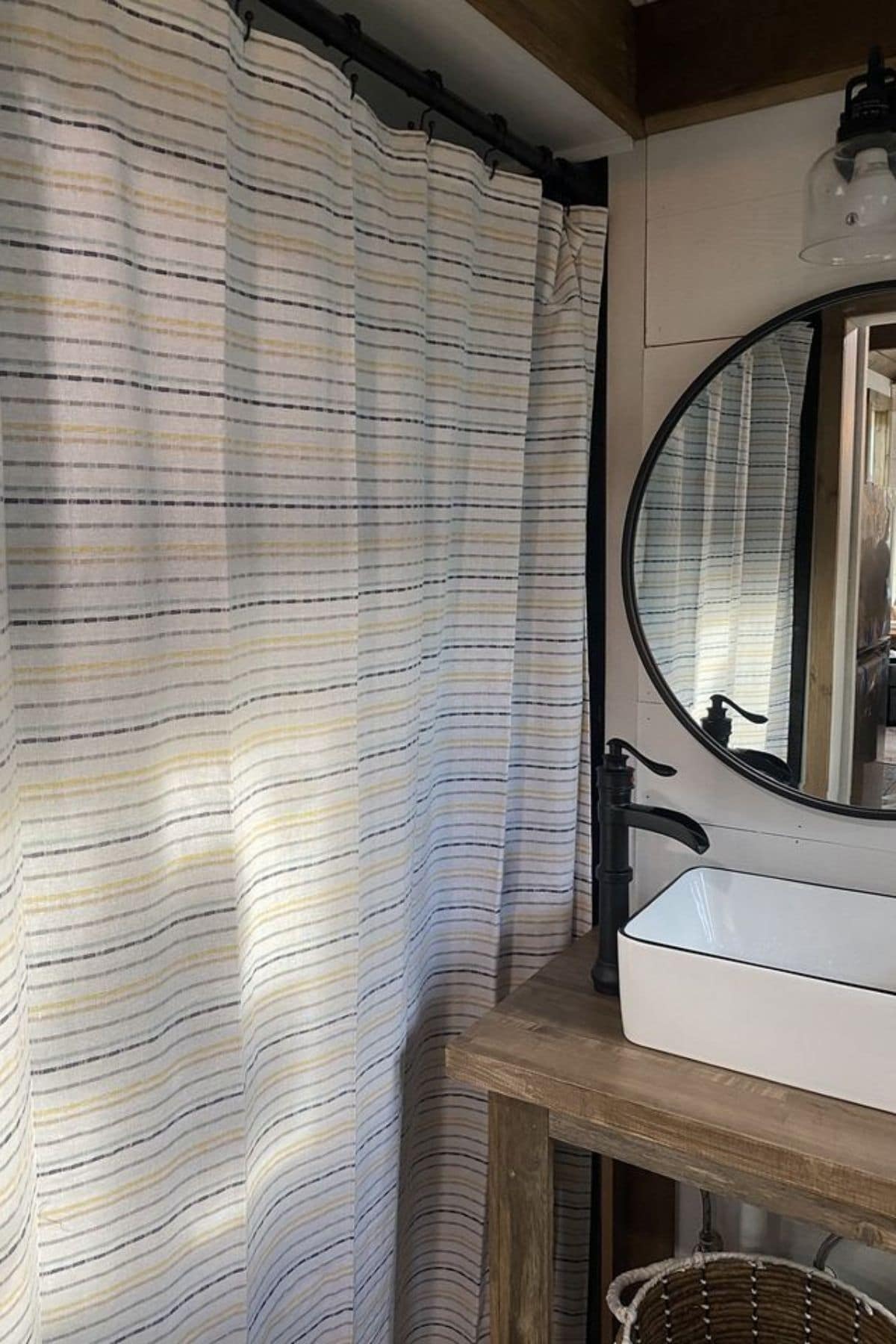 striped shower curtain next to wood vanity with white sink