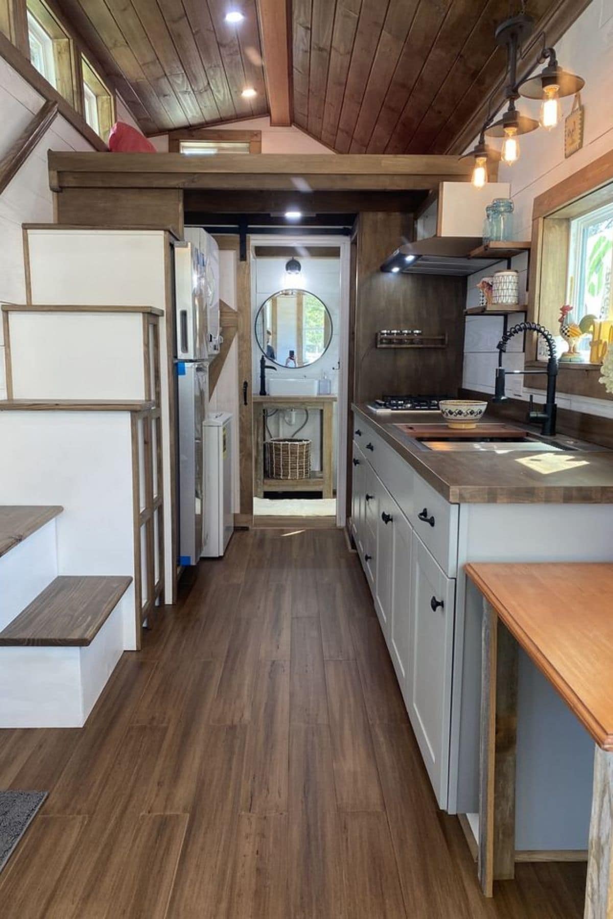 view into kitchen of tiny home with white stairs on left and counter on right