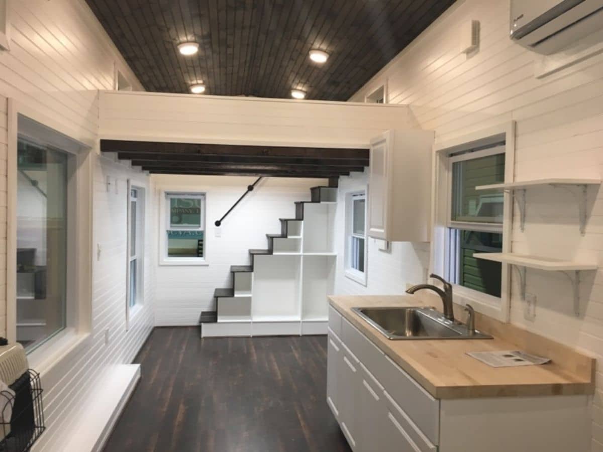 view of tiny home interior with kitchen on right and stairs at back of image