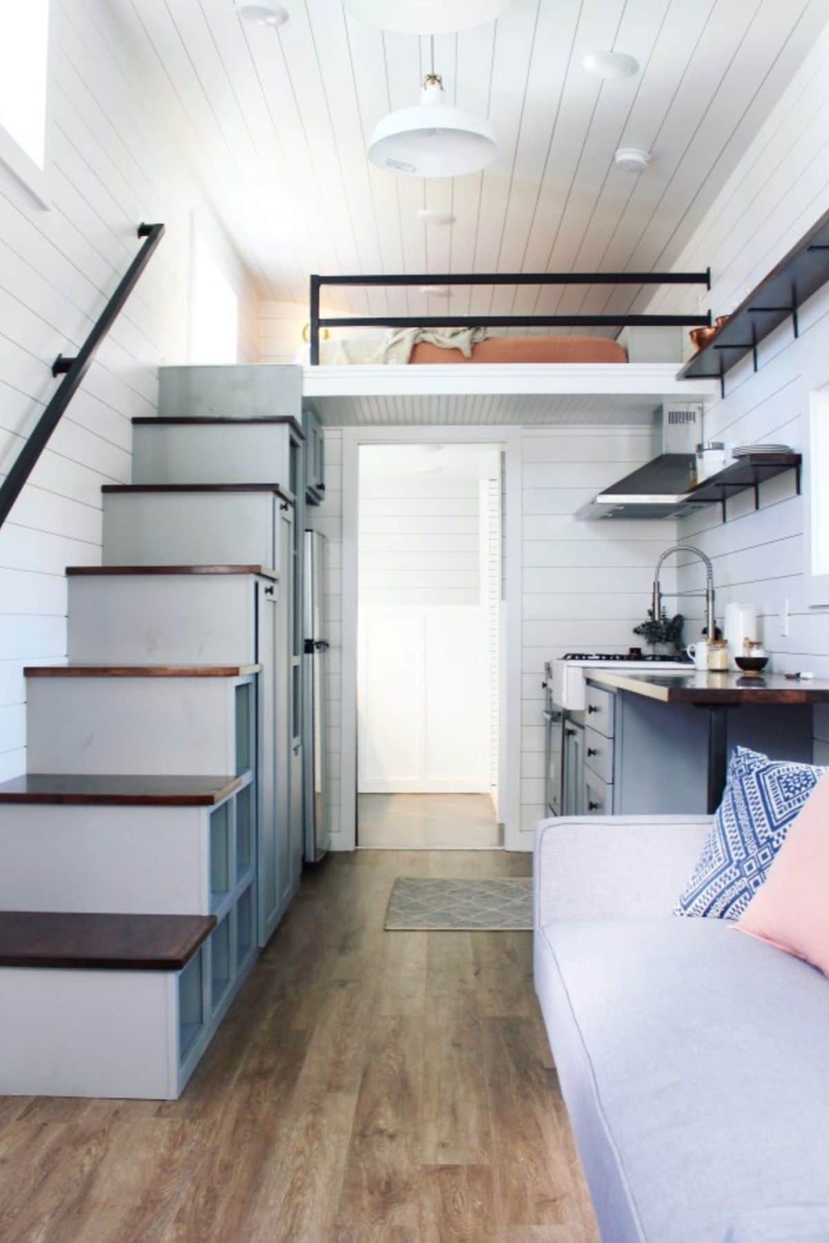 tiny home with white interior stairs on left and sofa on right