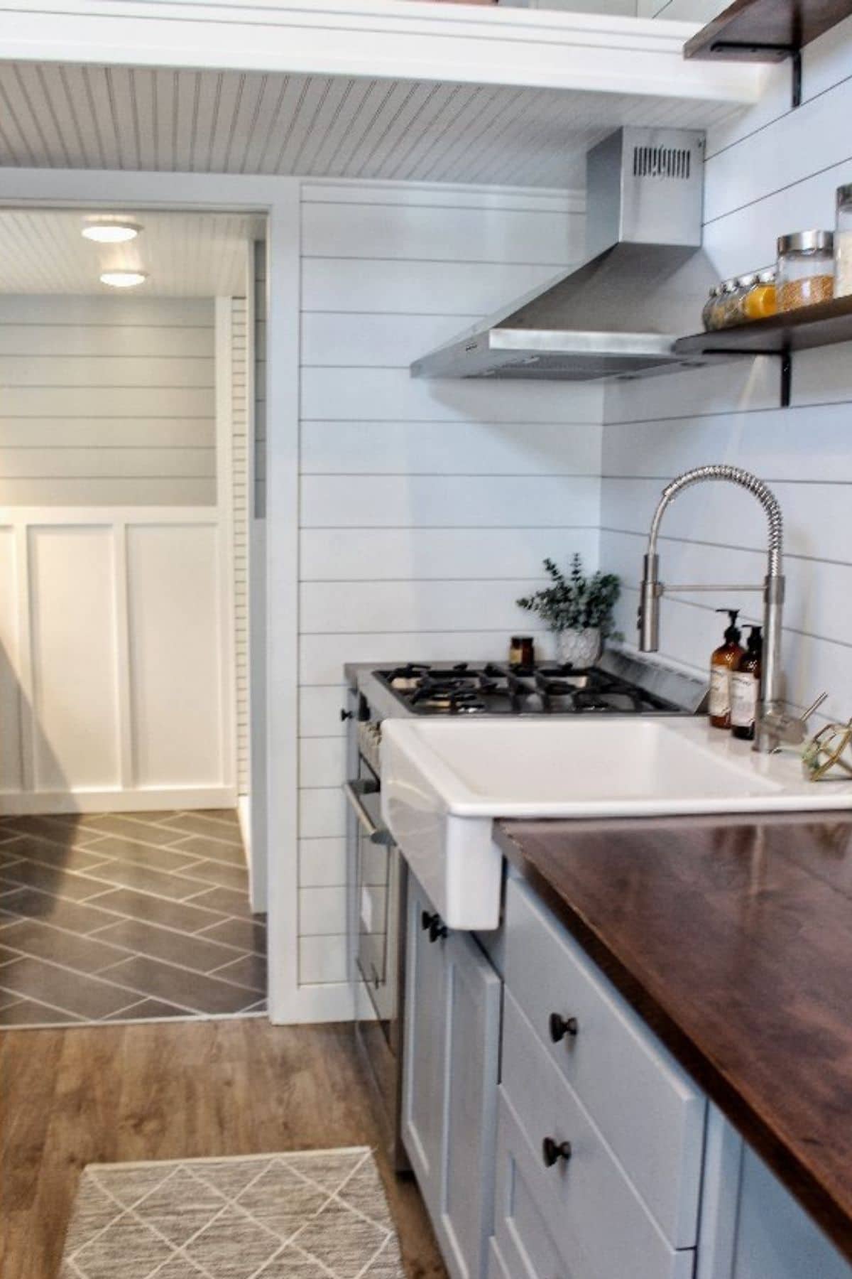white farmhouse sink in gray cabinets and wood counter
