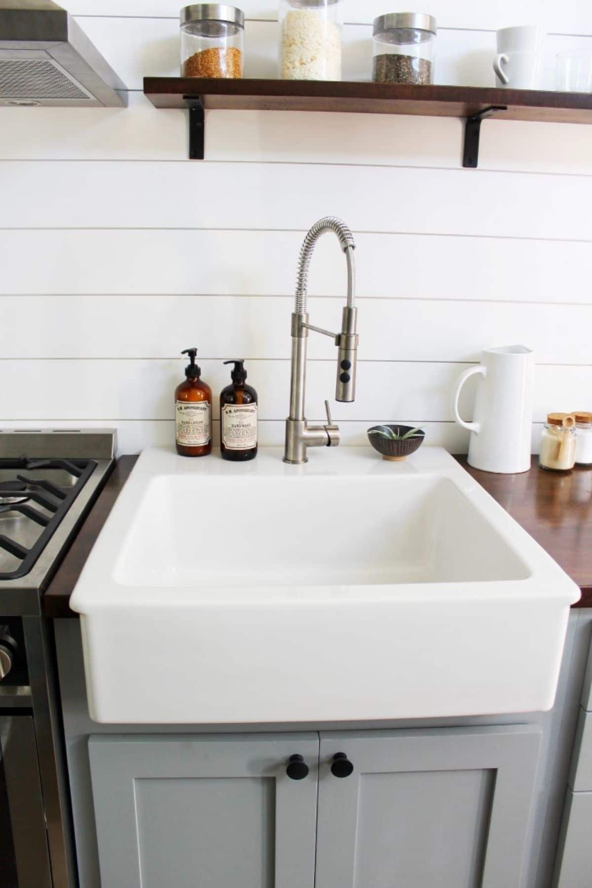 white farmhouse sink above gray cabinet