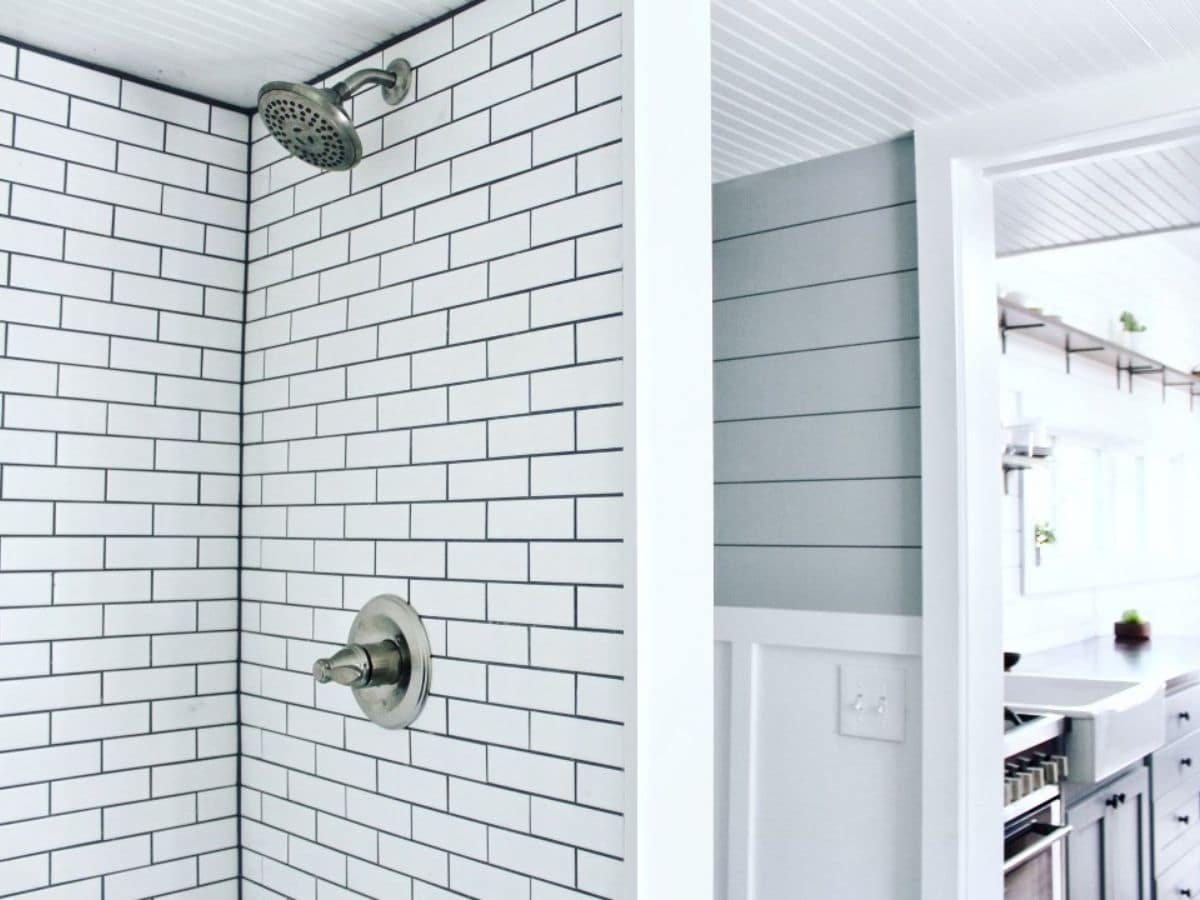 white subway tile shower against white and gray shiplap wall