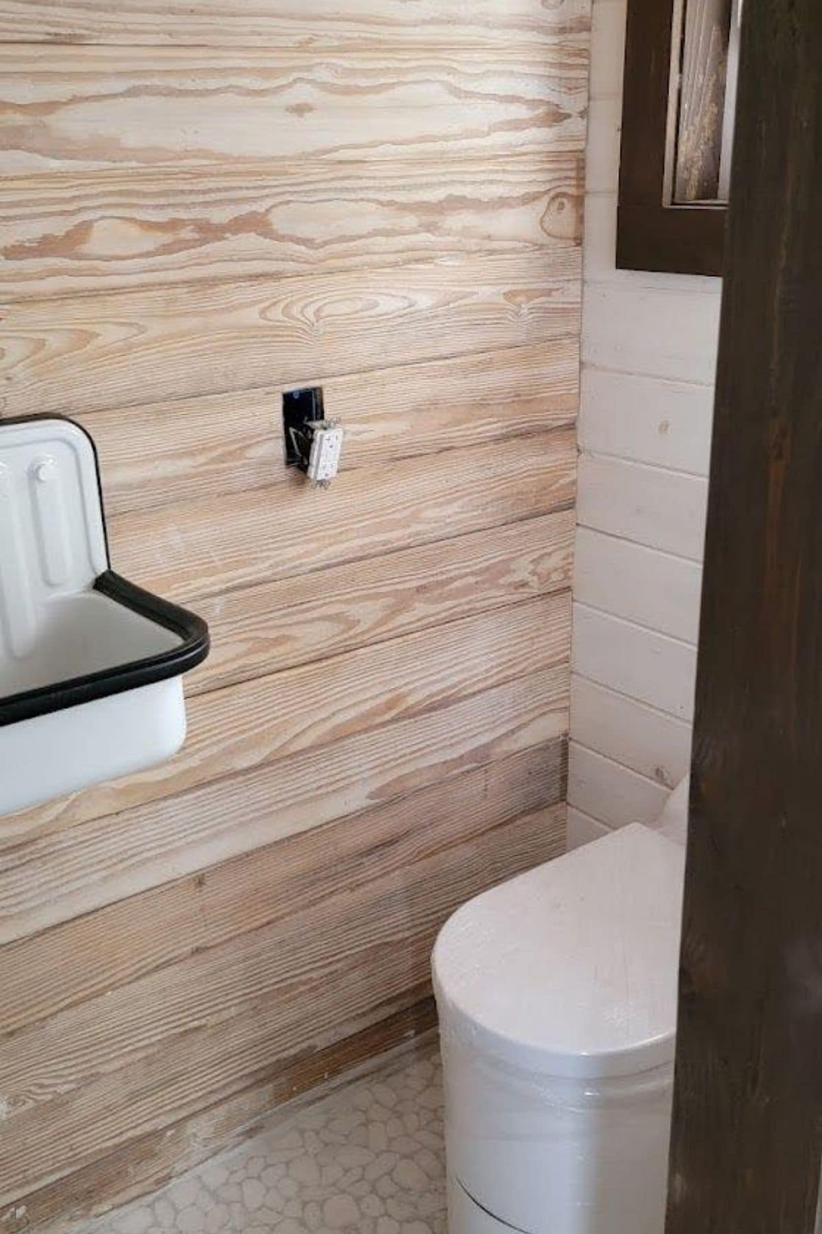 compost toilet in corner of bathroom with light wood wall