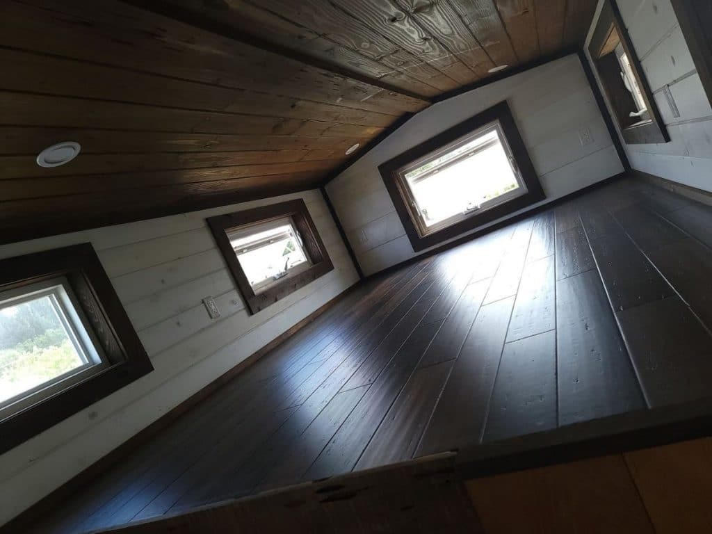 loft with wood flooring and white walls