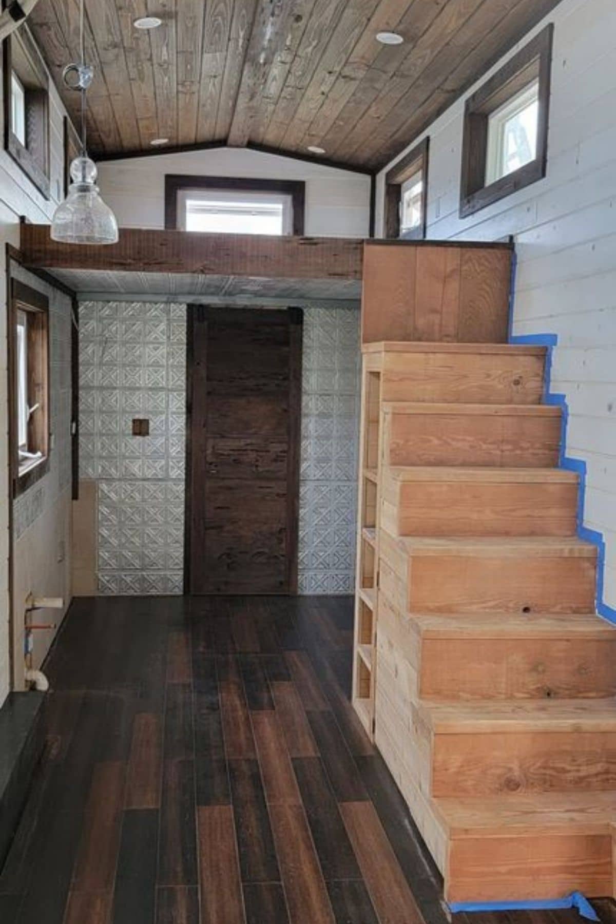 view of tiny home interior with stairs on right and bathroom door in background