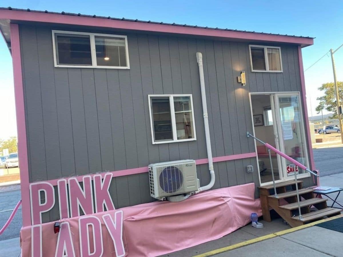 gray tiny home with pink trim and sign that says pink lady on side