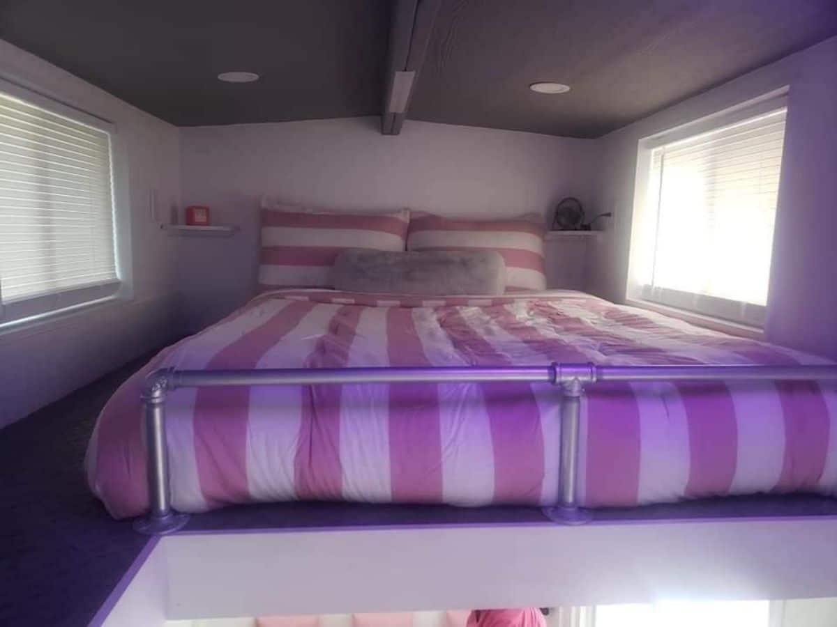 pink and white bedding on queen bed in loft with gray ceiling