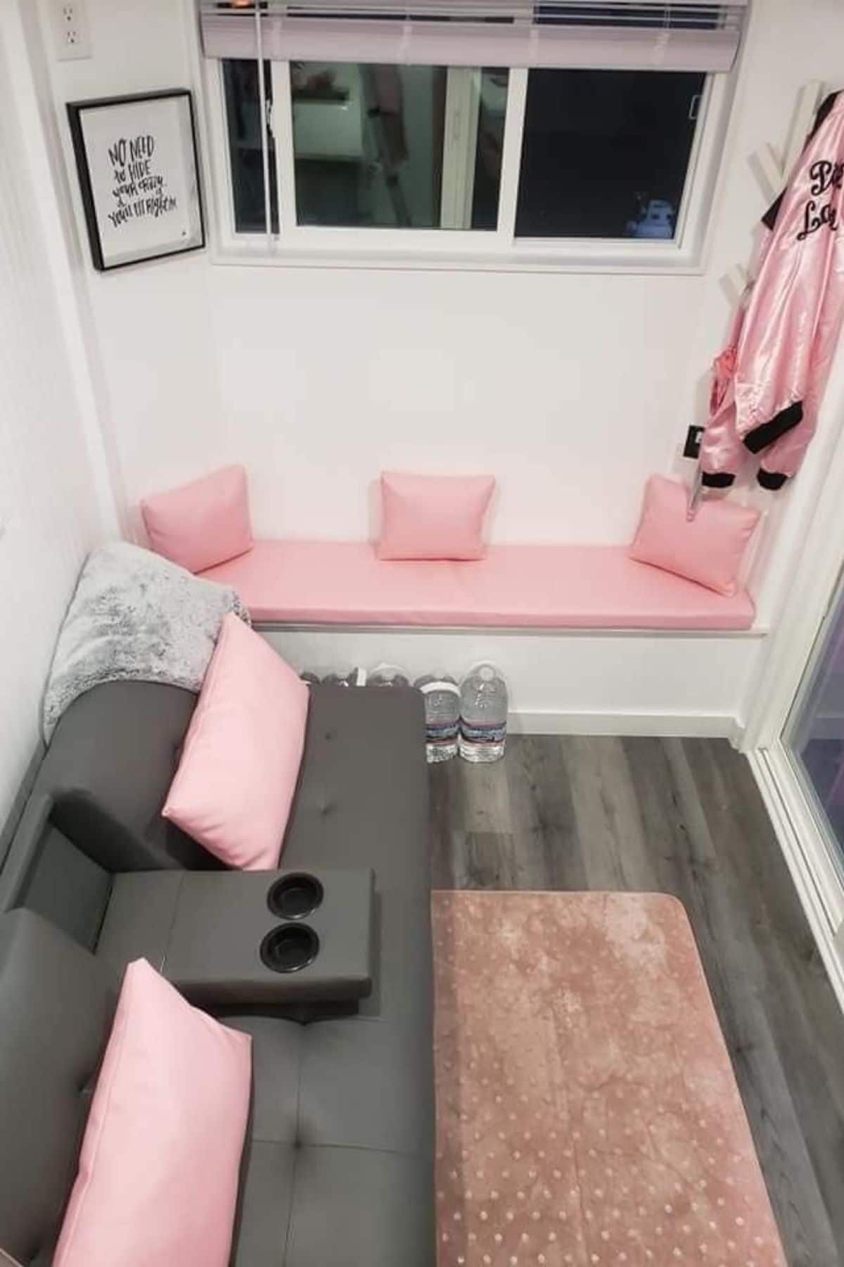 gray sofa with pink cushions against white wall