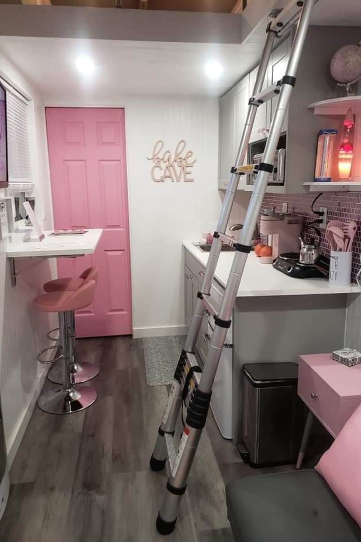 pink door at back with white walls counters and cabinets with pink stool accents