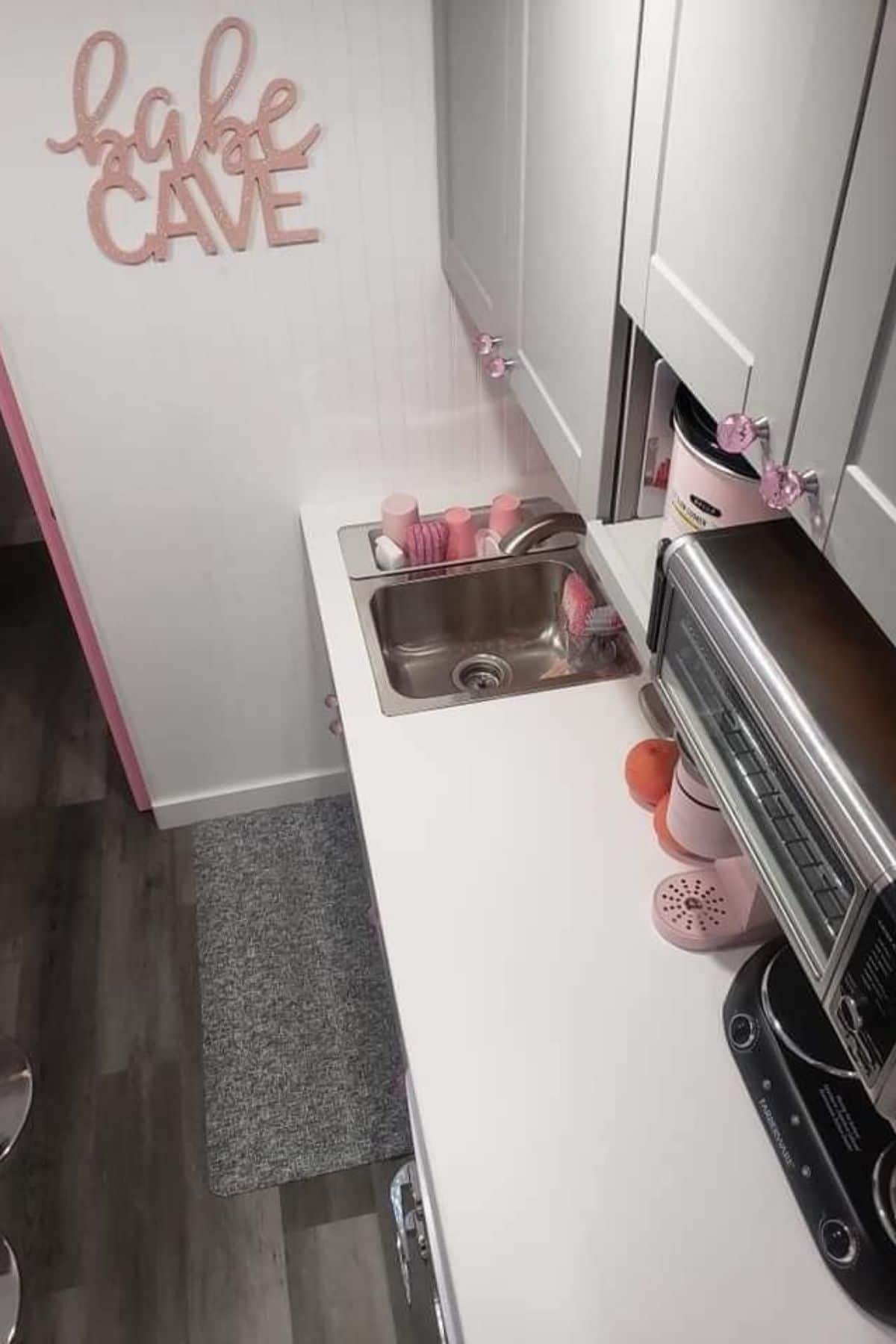 view looking down at kitchen counter with white cabinets and pink accents
