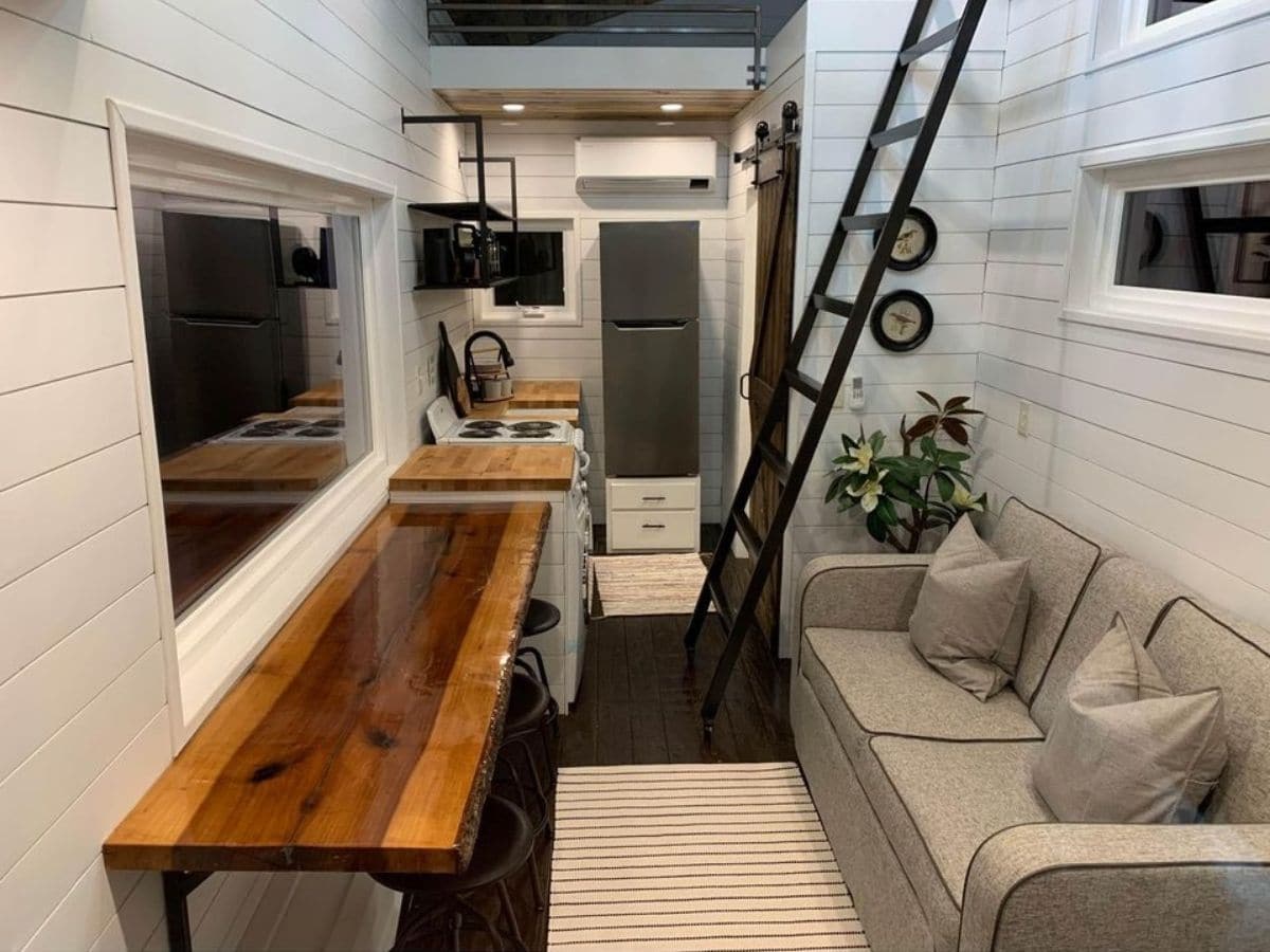 white interior of tiny home with dark wood table underneath window
