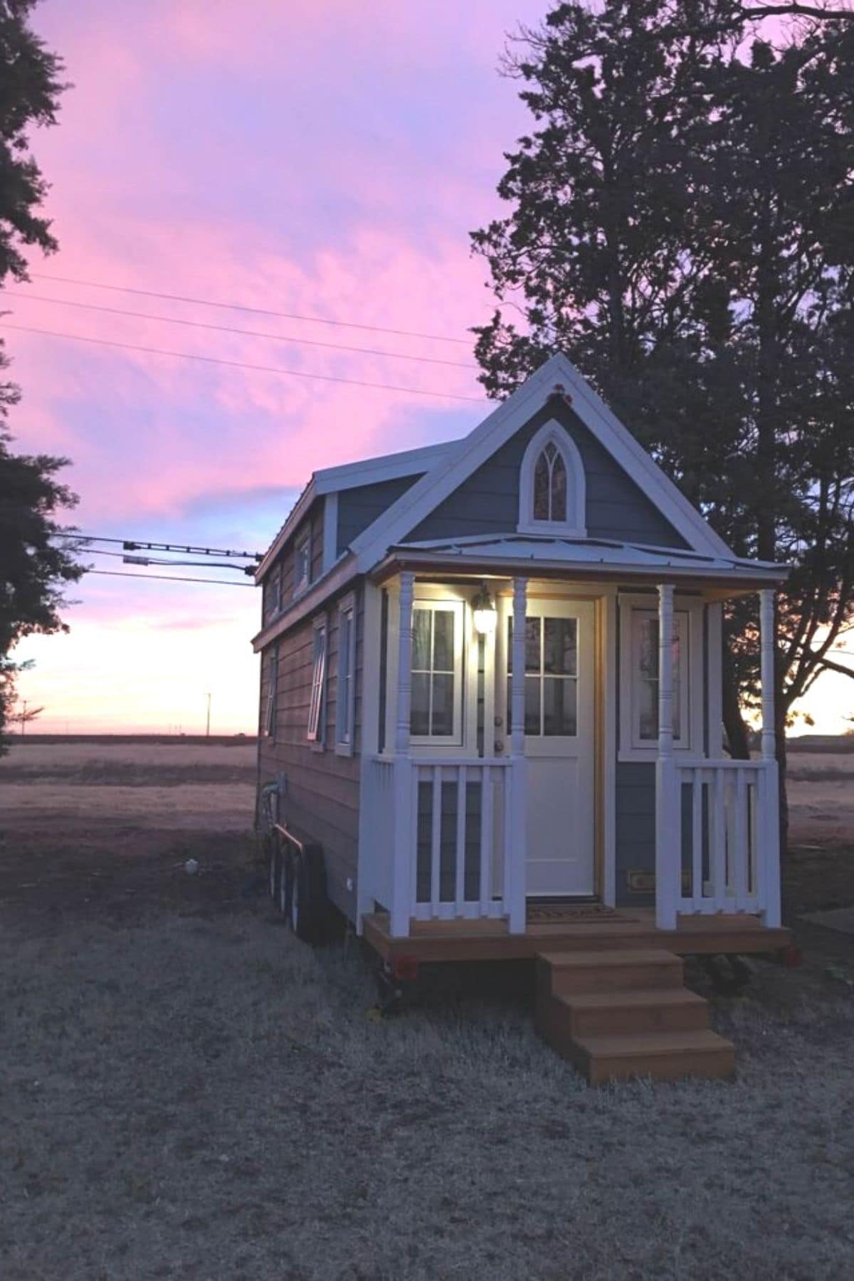 tiny home with porch and wood steps with sunset in background