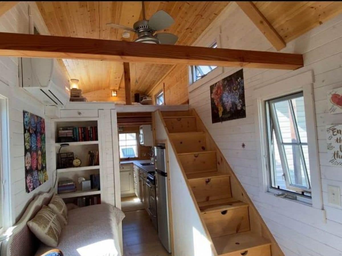 view into tiny home showing stairs on right and storage on left with loft in top background