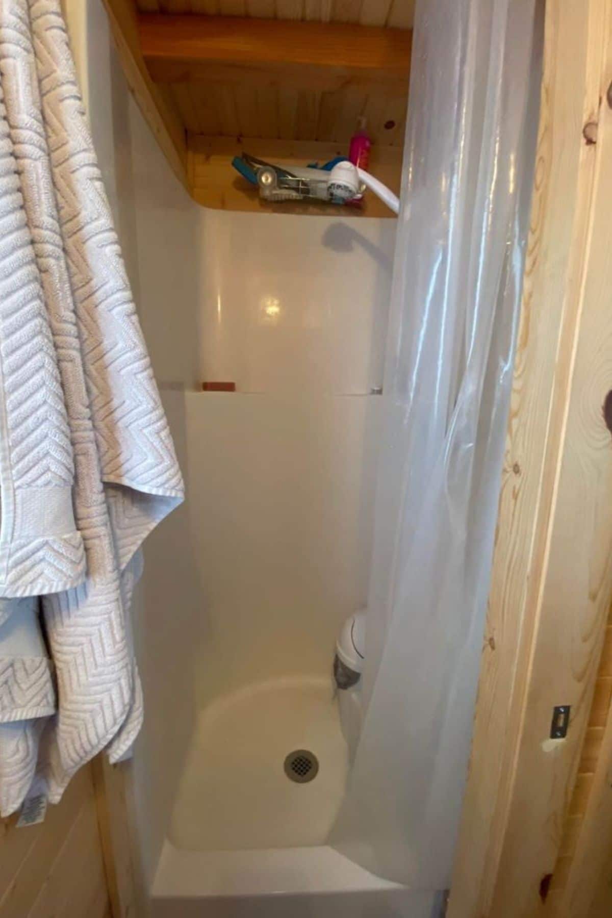 white shower stall with clear shower curtain and white towel hanging on left