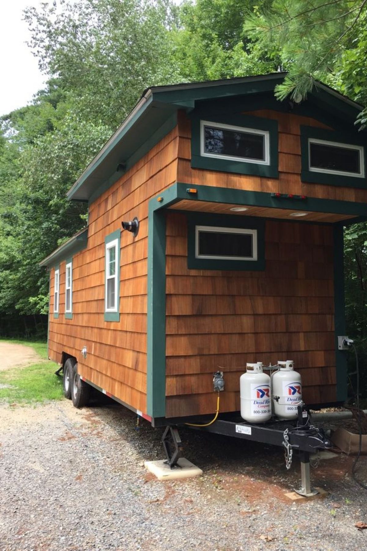 end of tiny home with cedar siding parked by trees