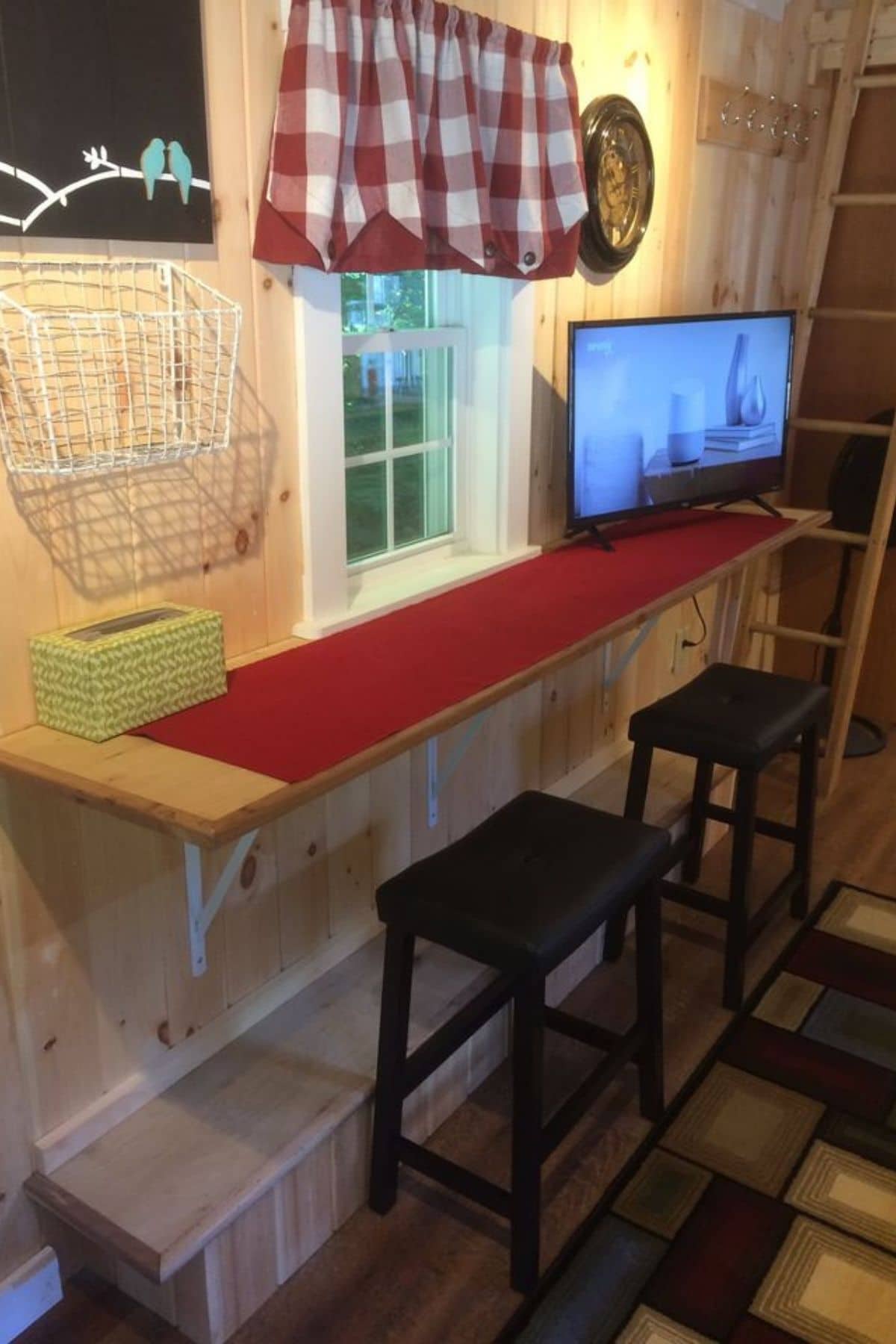 counter under window with two stools beneath and red tablerunner on top