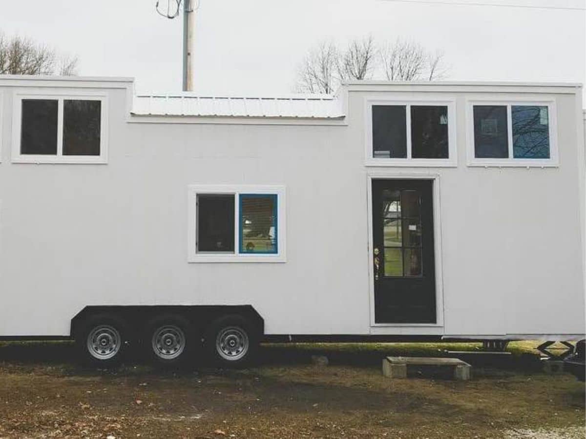 white tiny home on triple axel with two lofts