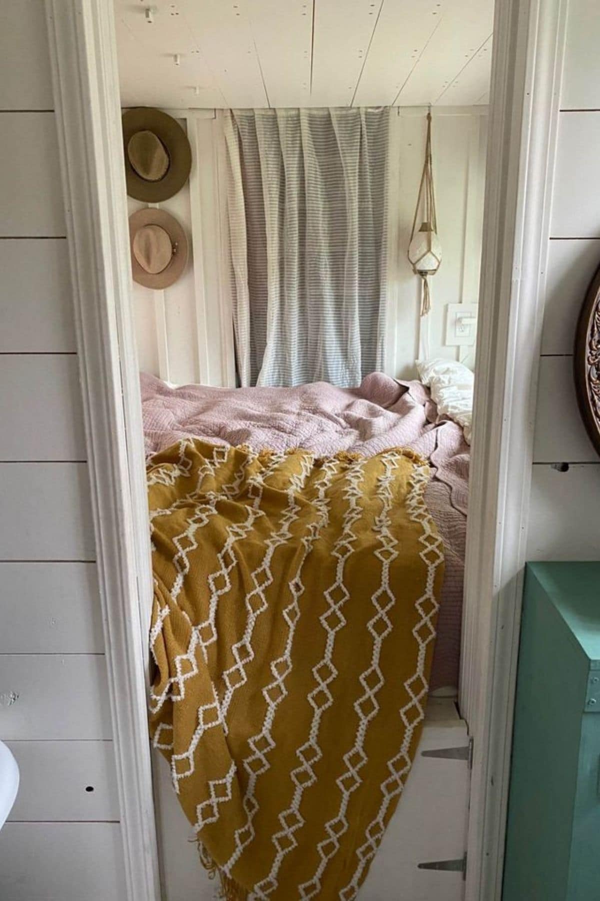 view into bedroom with yellow blanket on bed and teal shelf to right of door