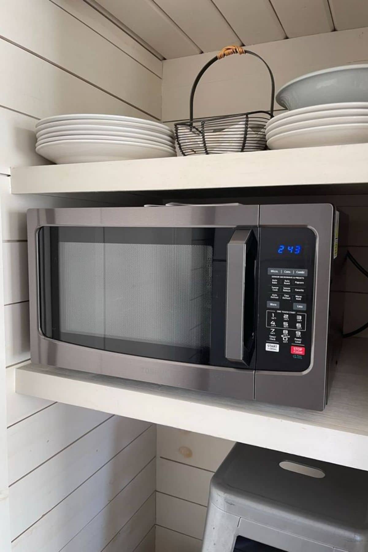 stainless steel microwave in white shelves