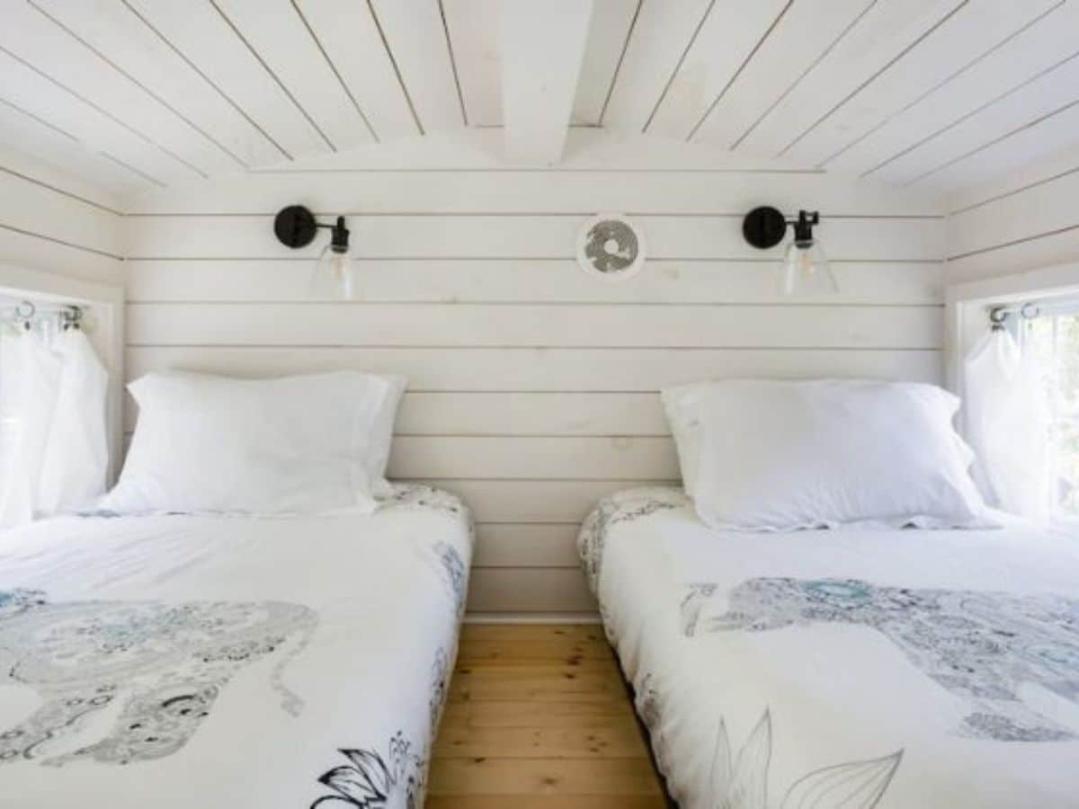 twin beds against white walls in loft with light wood flooring