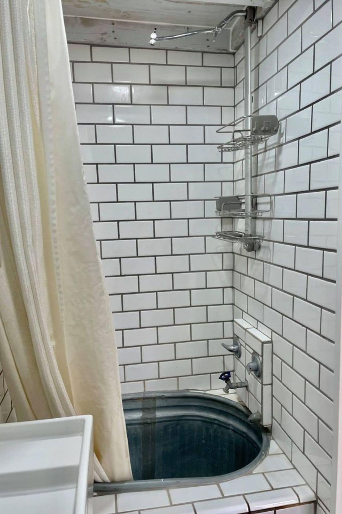white subway tile shower in shower with galvanized tub base and white curtain