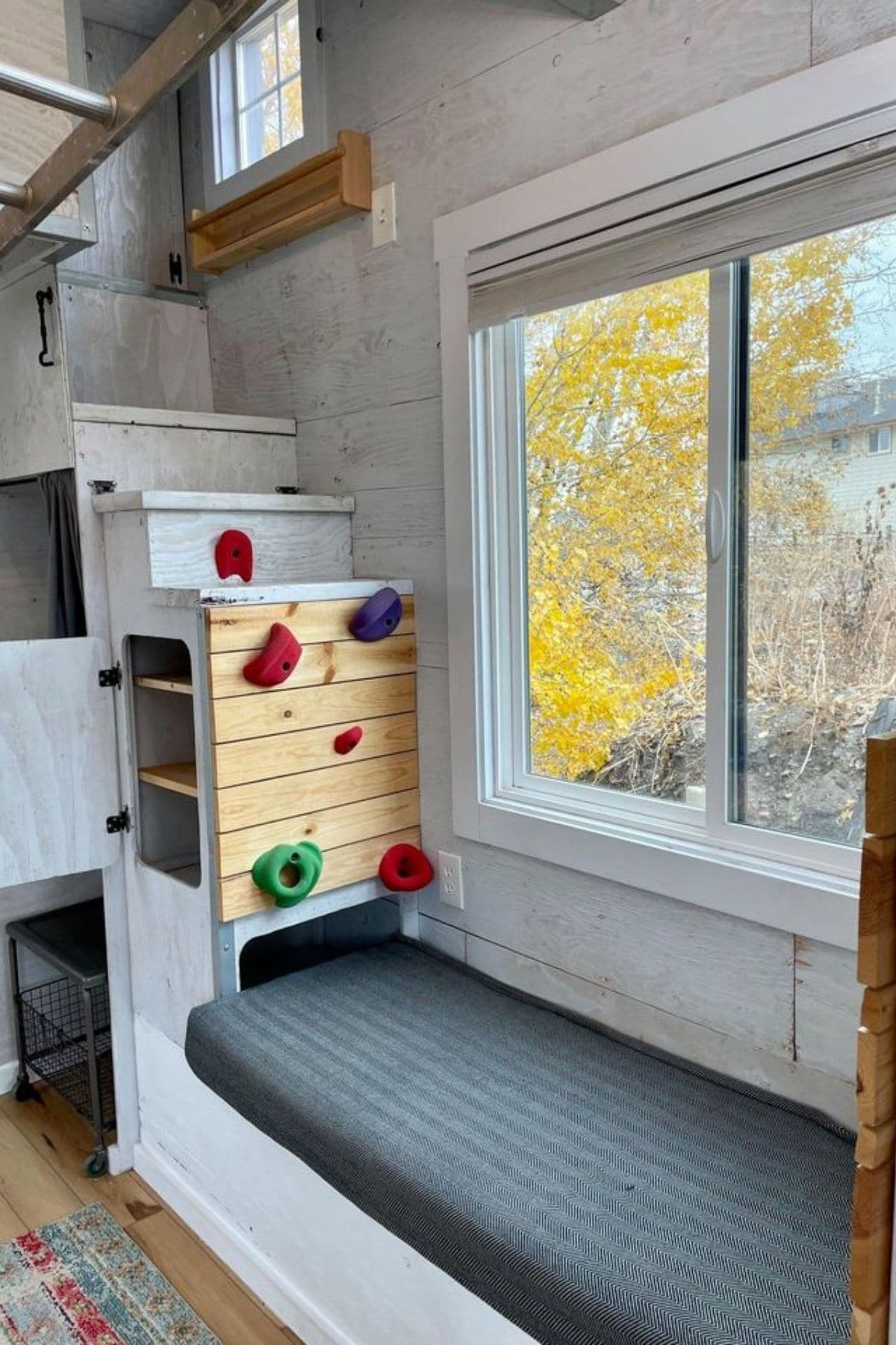 gray bench seat under window with stairs to loft on end